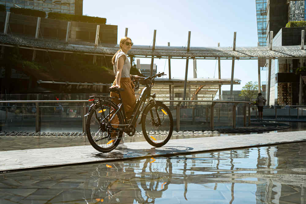 a woman stand besides her electric bike