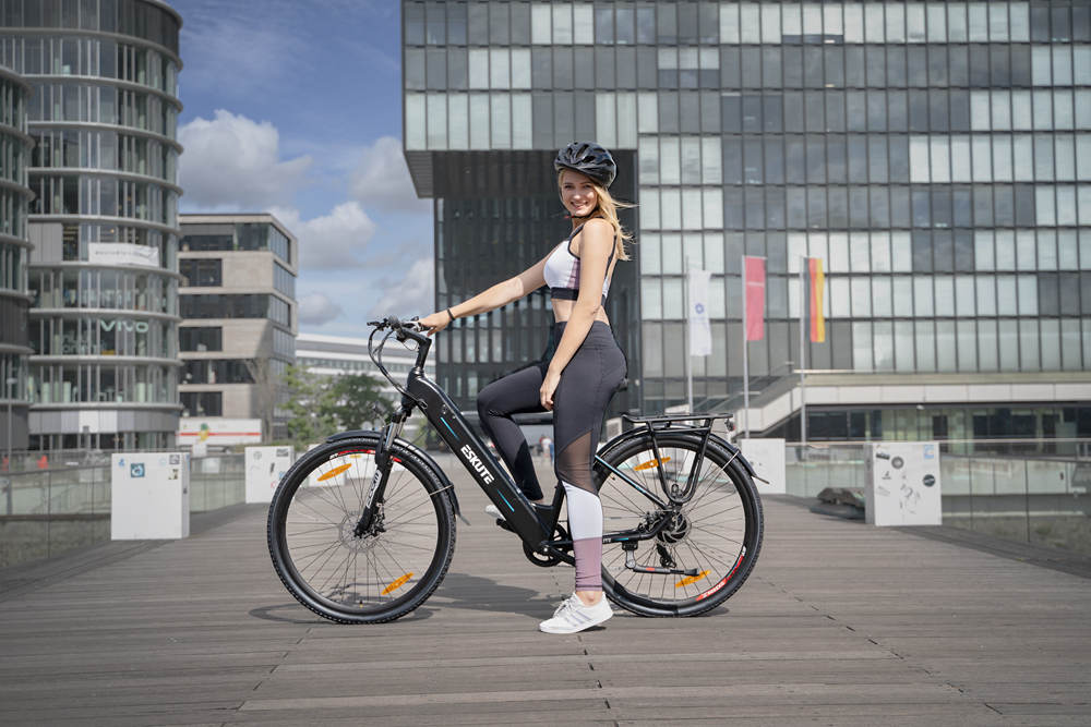 A lady sits on her electric hybrid bike in front of buildings