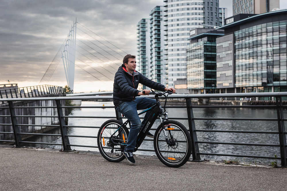 a man is riding his e-bike beside the river in the city