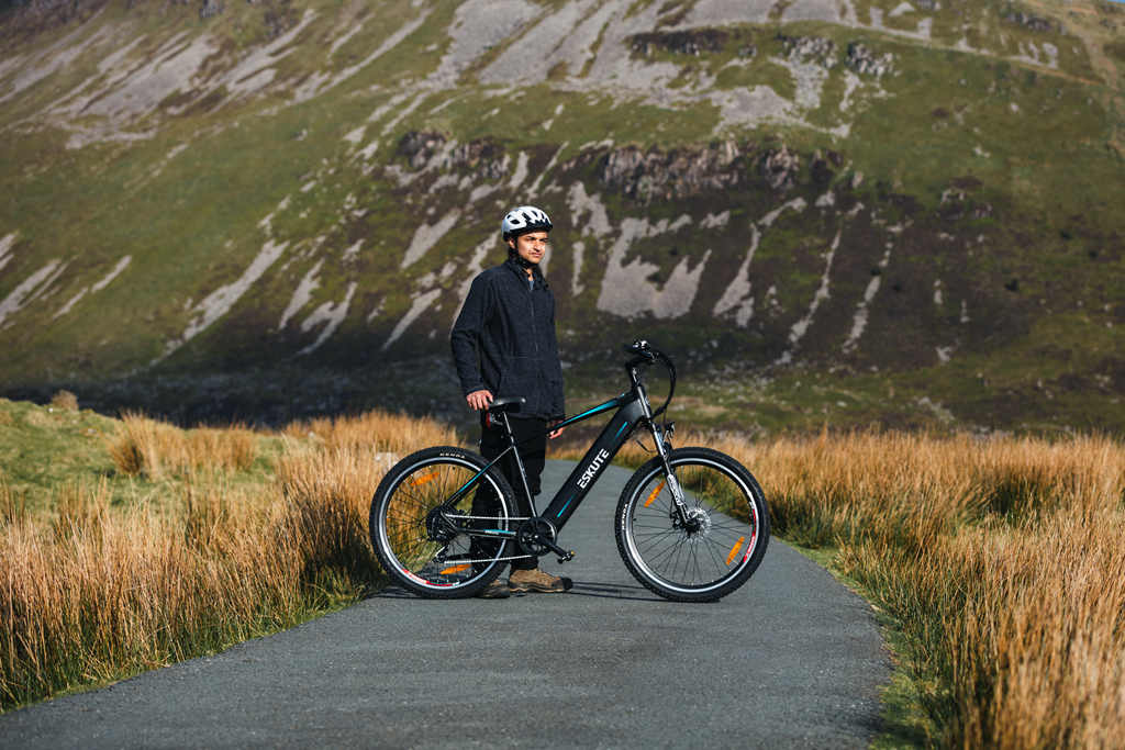 a man stands besides an eskute electric bike