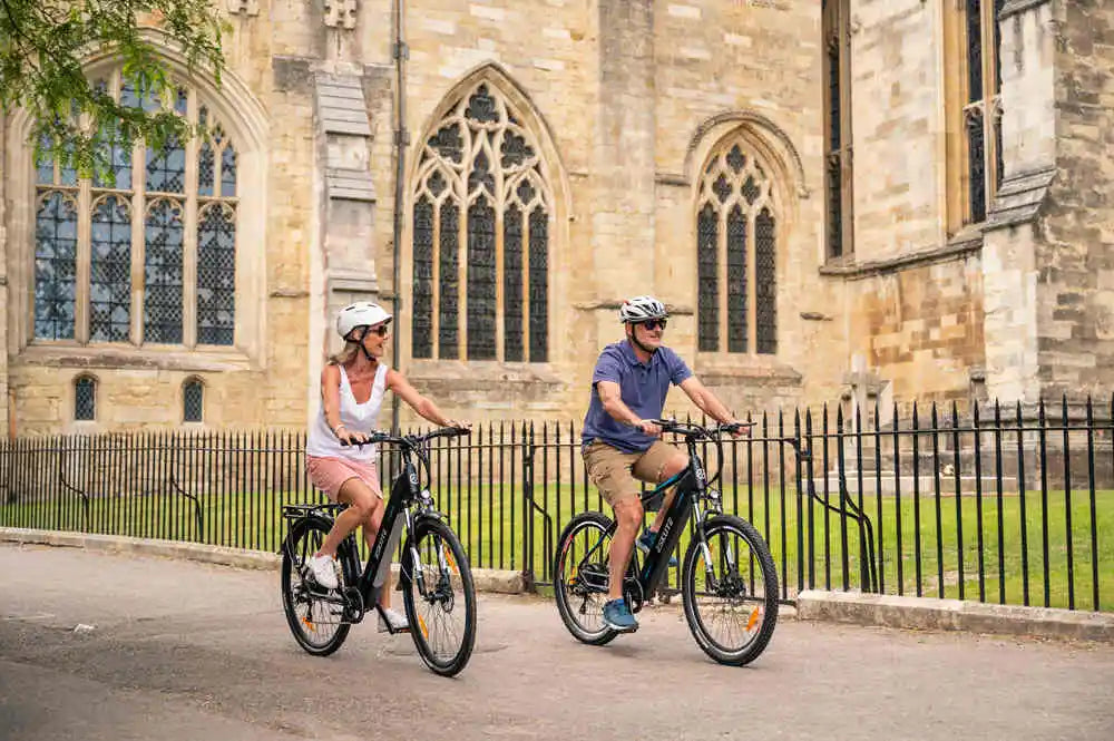 a man and a woman are riding their ebikes on the road