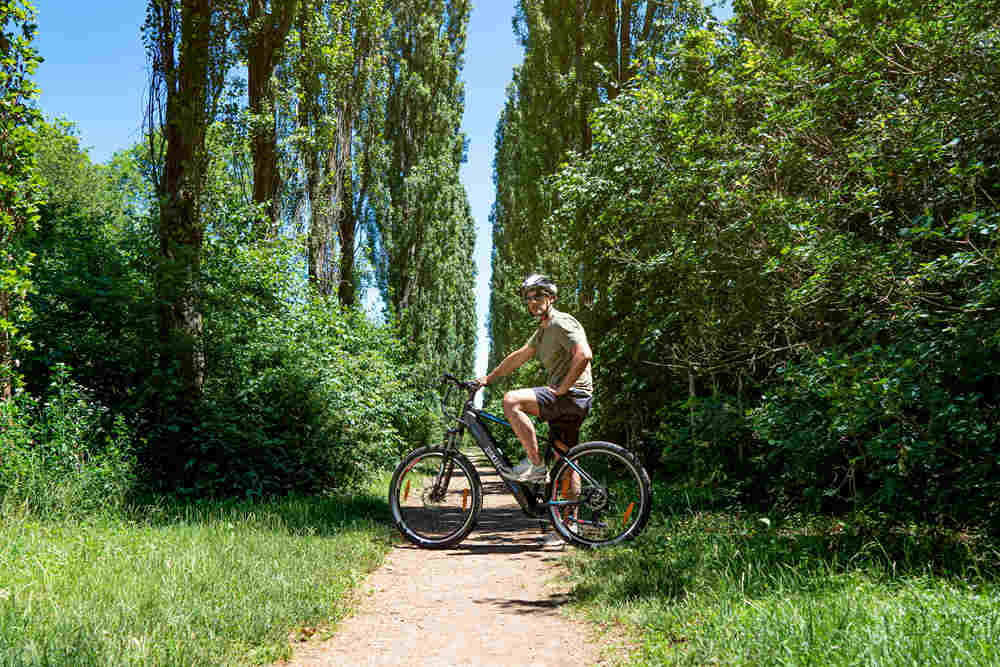 a man stops his electric bike in the shady path