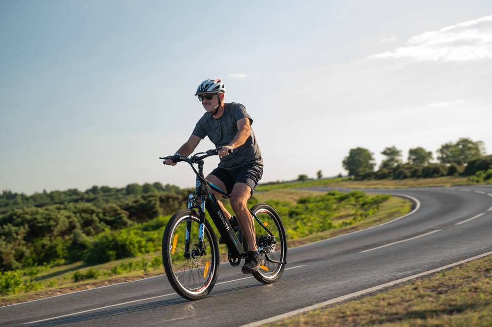 a man with a helmet is riding Torque Sensor e-bike on the downhill road