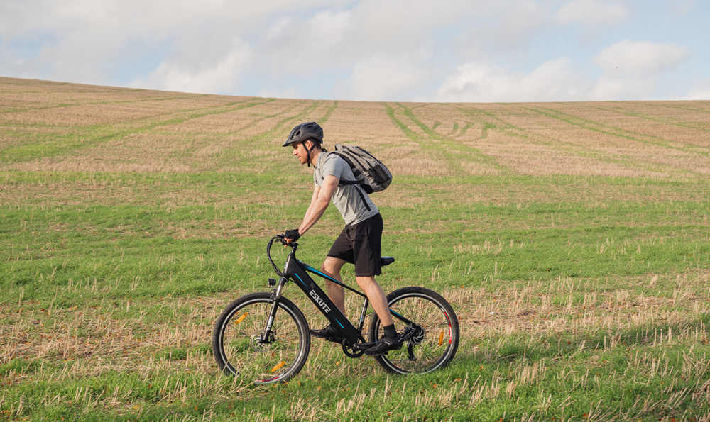 a man with helmet and backpack is riding his best emtb on the grassland