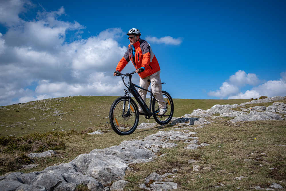 a man with helmet is riding netuno ebike on the mountain top