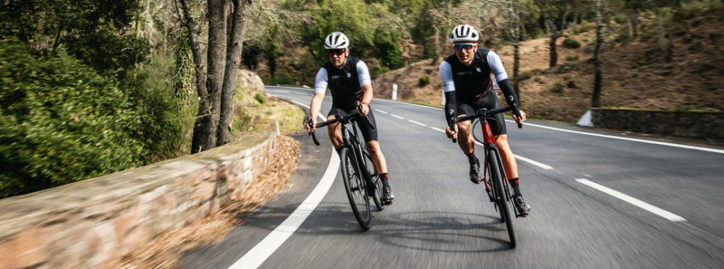 two men ride road e-bikes on the road